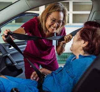 Caregiver assisting senior into car