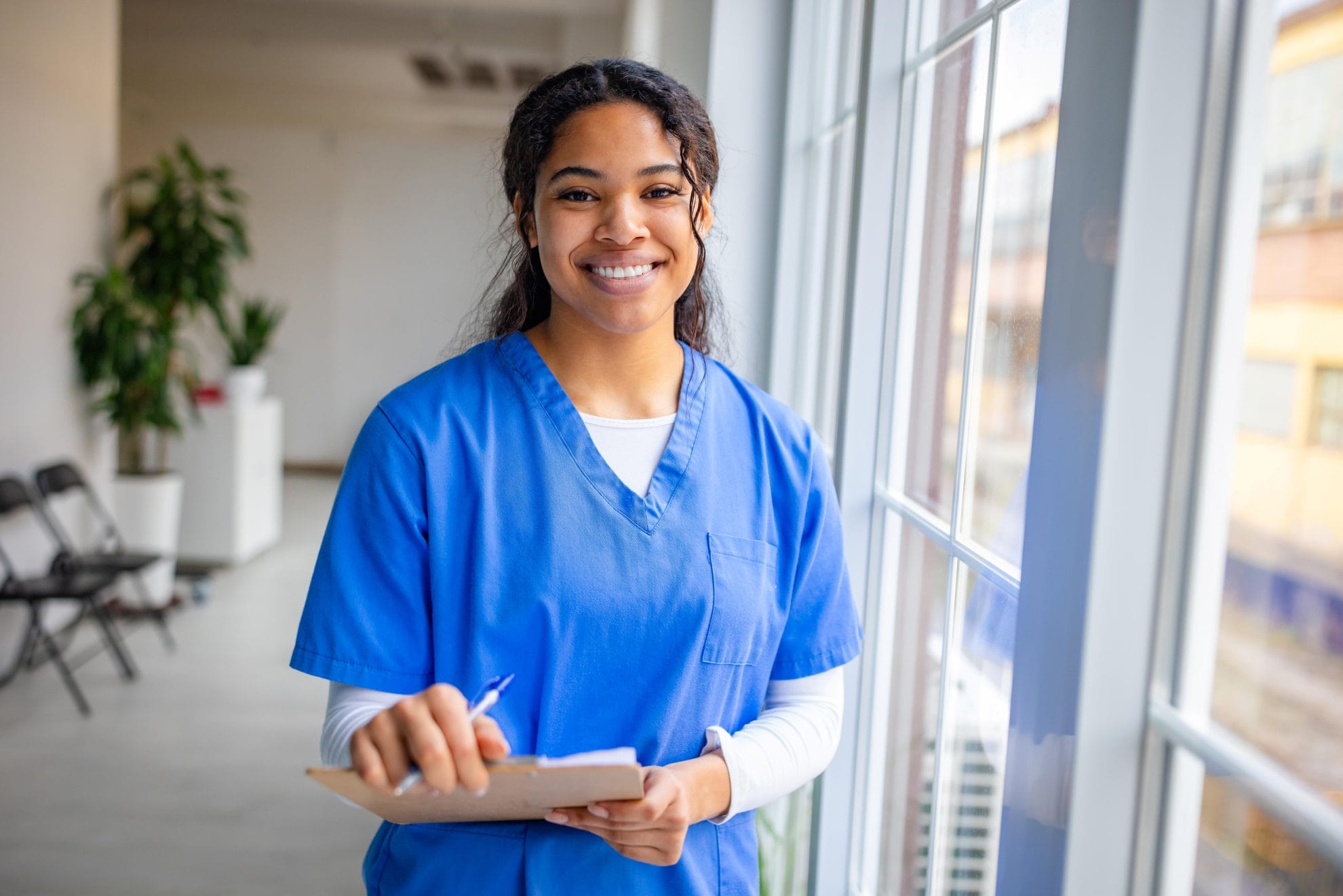 Caregiver smiling and holding clipboard.