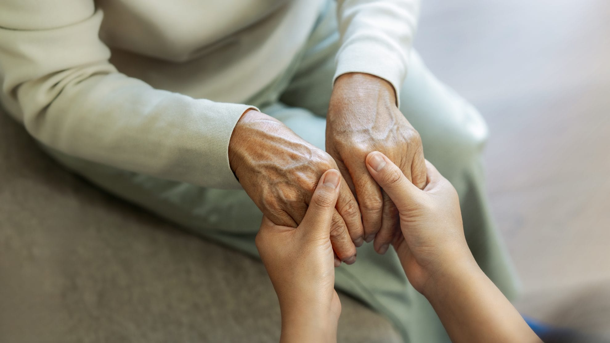 Caregiver holding elderly woman's hands.