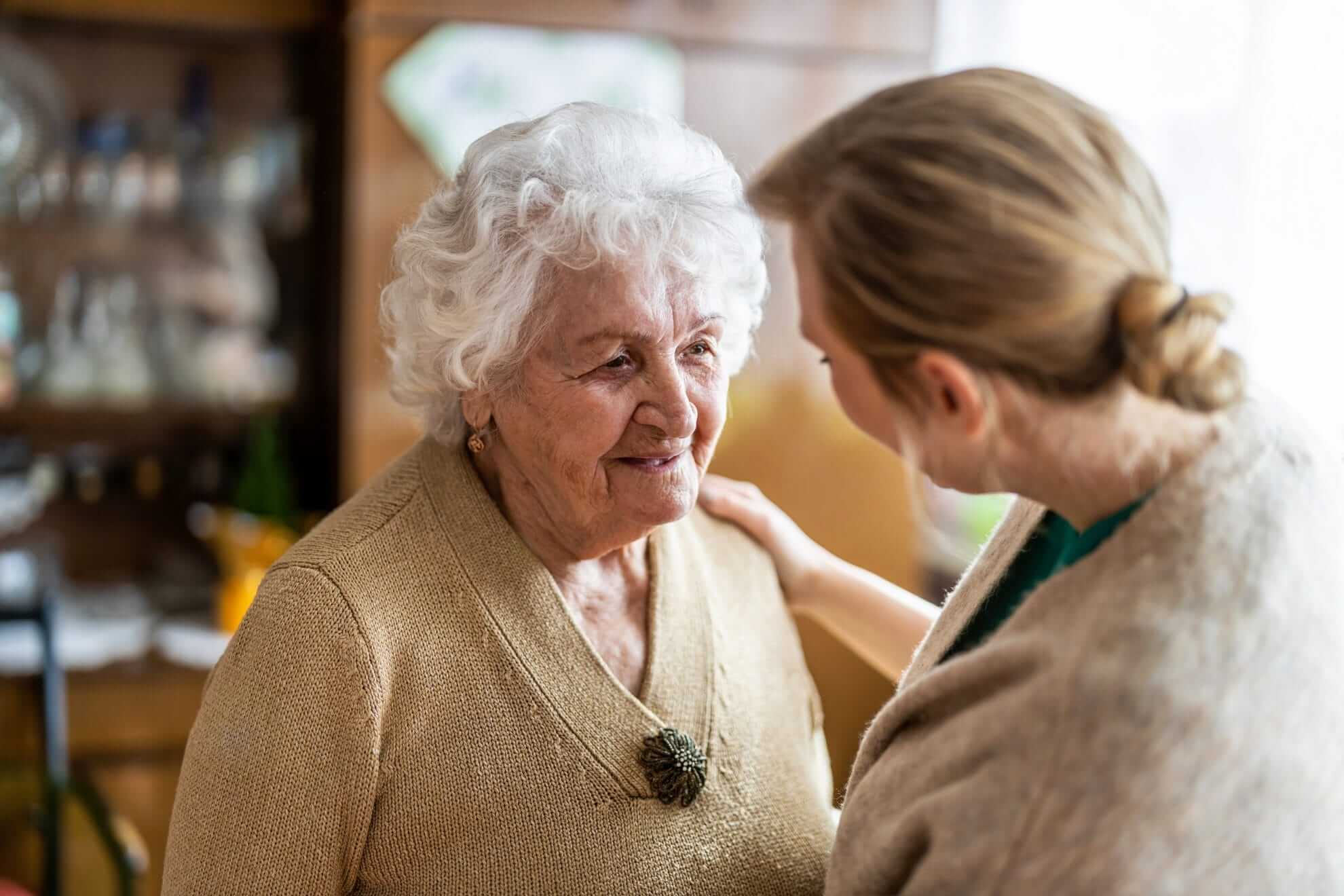 Caregiver talking to senior woman during a home visit.