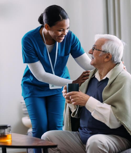 Nurse assisting elderly man at home