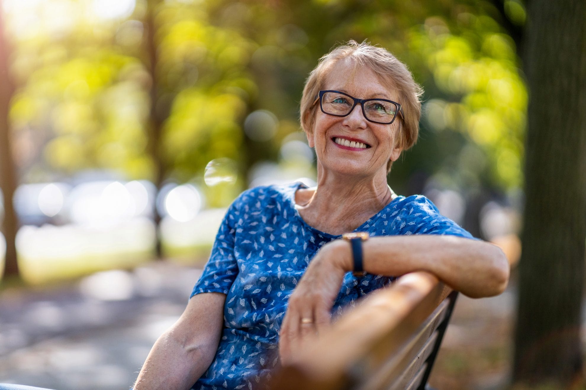 Smiling senior woman sitting on a park bench.