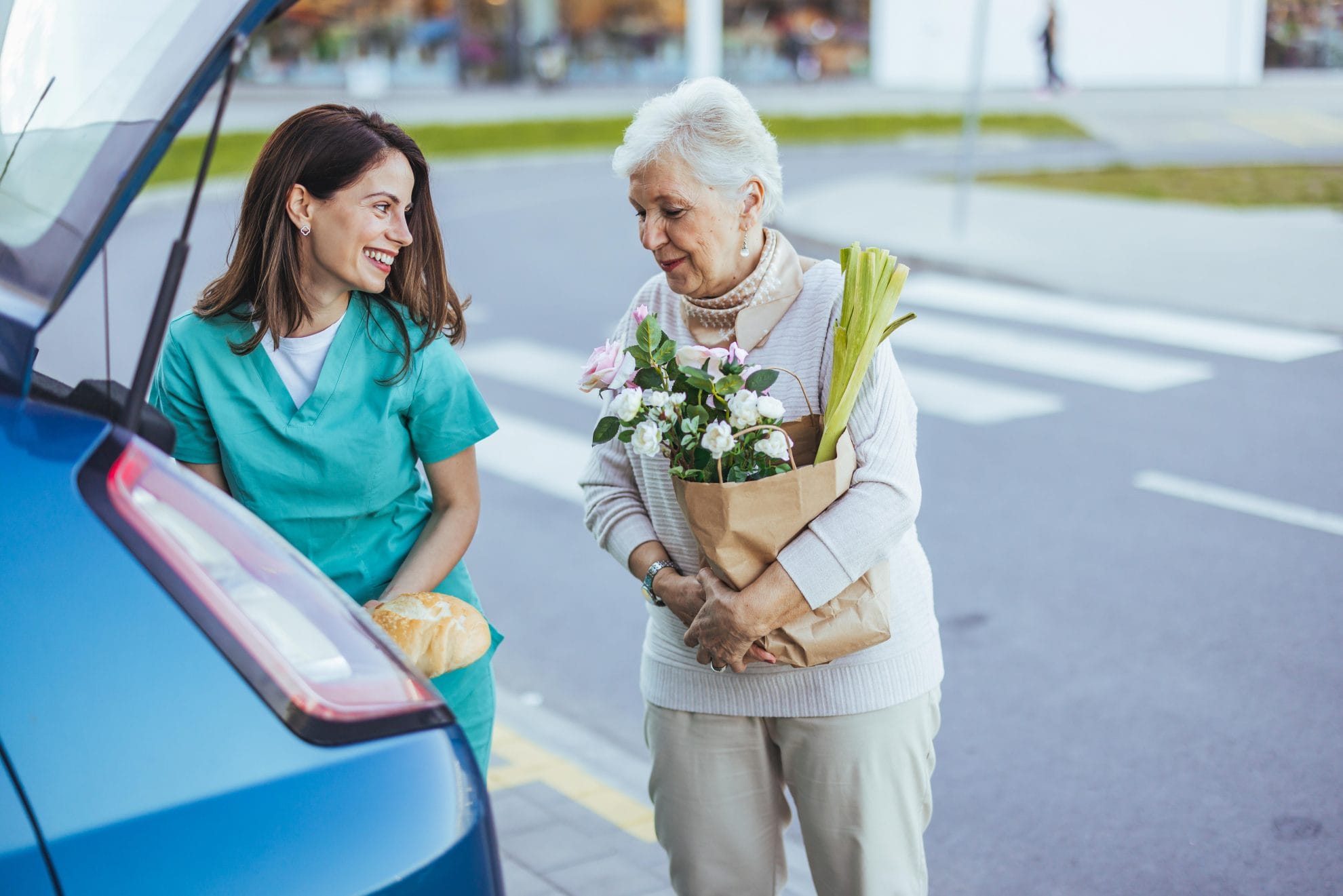 Caregiver assisting senior woman with groceries.