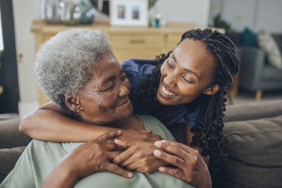 Caregiver embracing elderly woman.