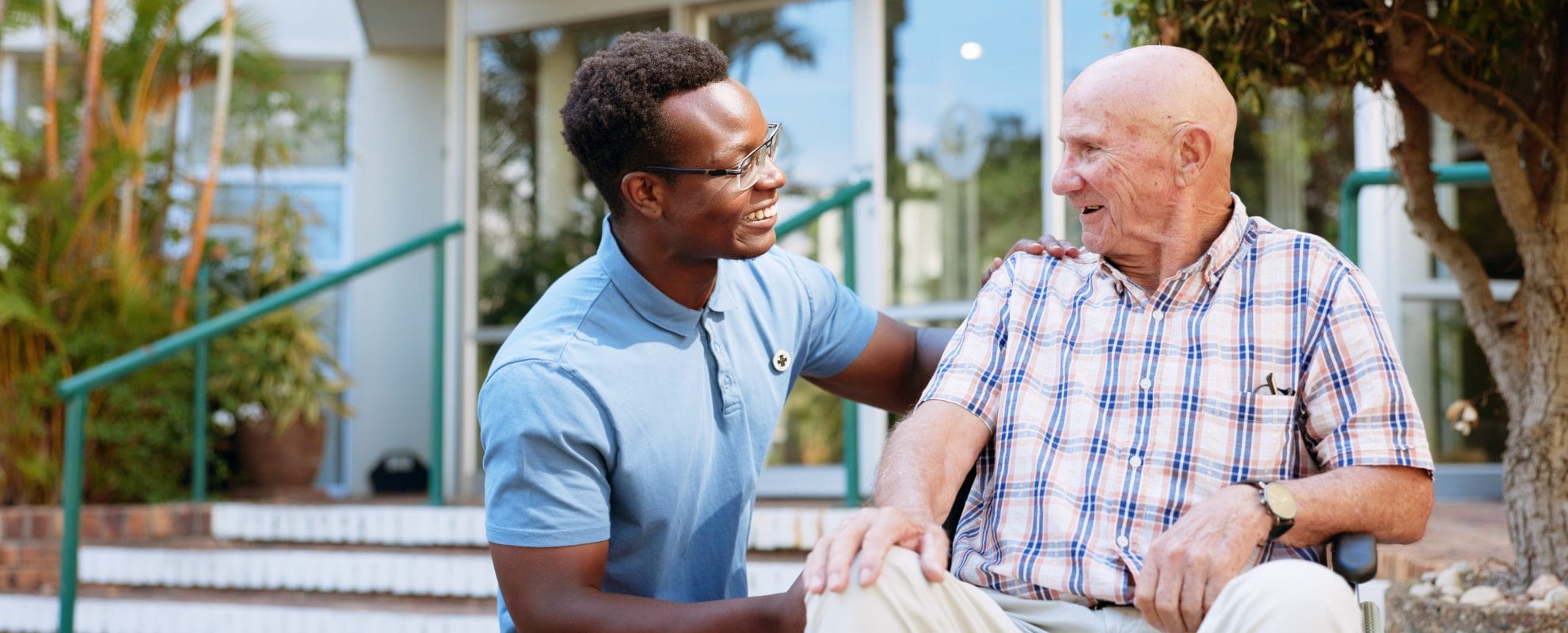 Male caregiver assisting elderly man in wheelchair