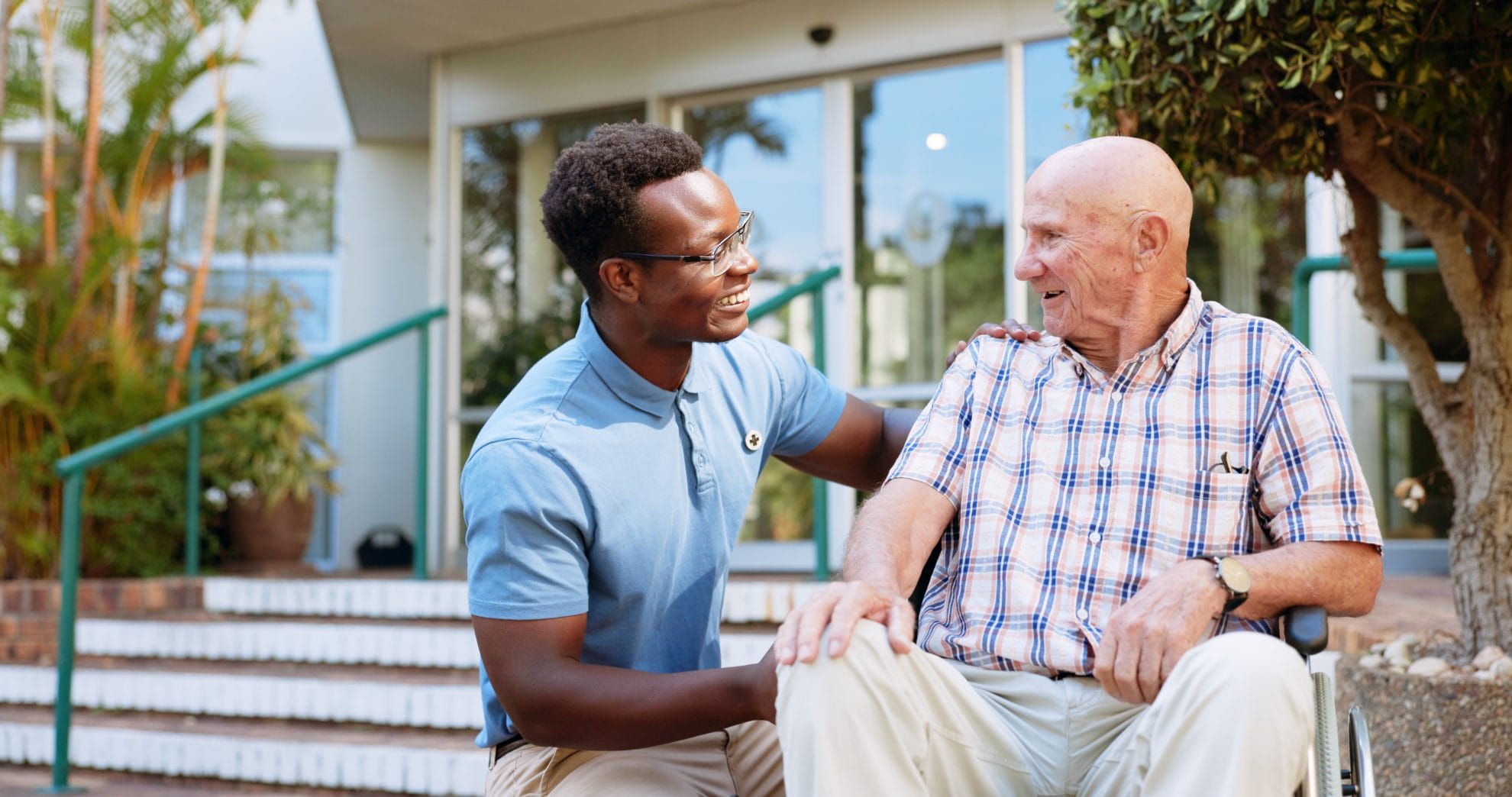 Caregiver assisting elderly man in wheelchair.