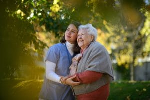 Nurse and senior walking outdoors